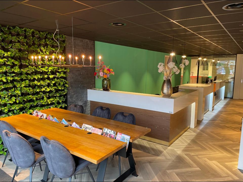 Ontvangstruimte met hanglampen, inbouwspots en een lineaire armatuur boven een tafel.
