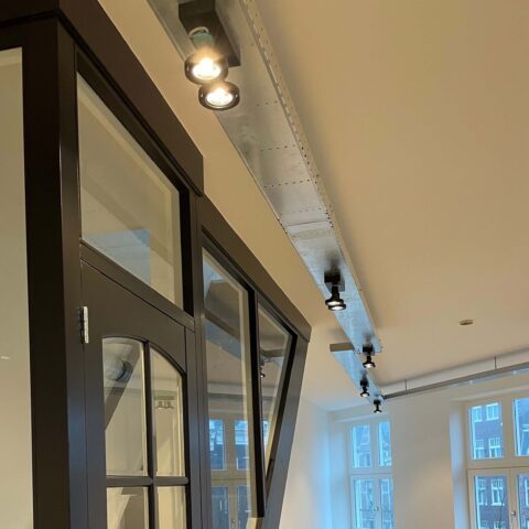 Rail met spotverlichting langs een plafond, met de aansluitpunten zichtbaar.